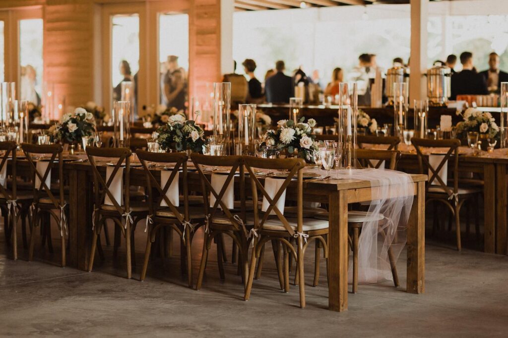 barn interior with doors and windows open to outside, set up with long wood tables and chairs for wedding reception